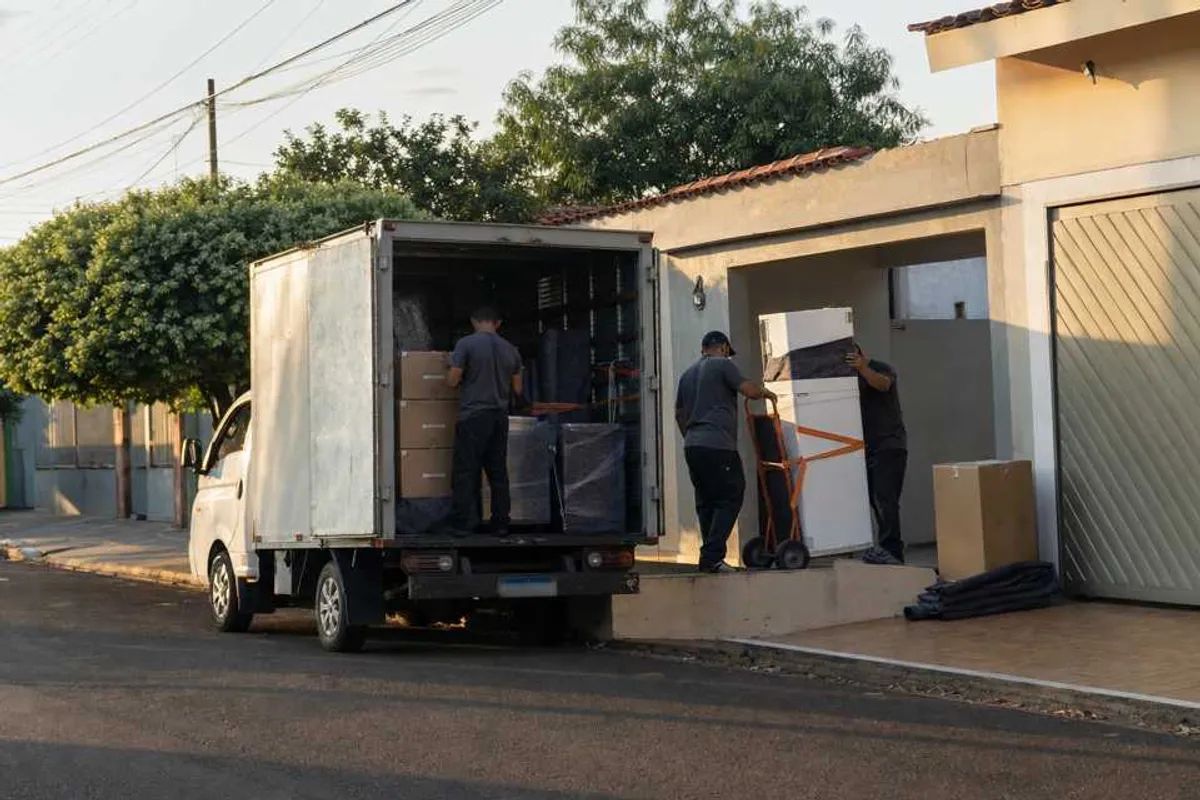 Equipe de frete organizando caixas e eletrodoméstico em caminhão pequeno na Vila São Francisco, Dourados